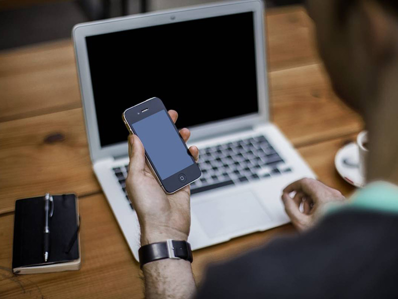 Man using a laptop and a phone to schedule oahu dump run